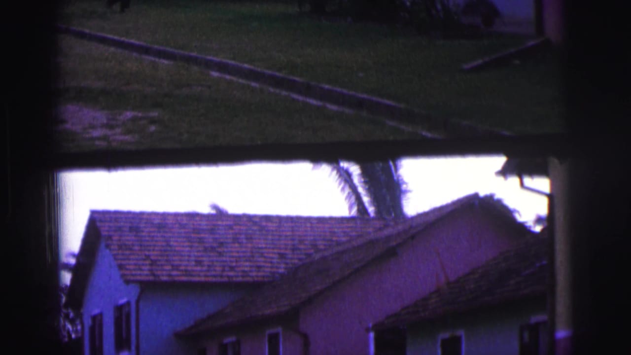 Pastel houses with tiled roofs seen through a dark window-like frame.