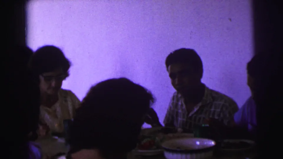 Brazil 1967 dinner scene with seated adults, tableware, food, and a strong purple cast from the film or lighting.