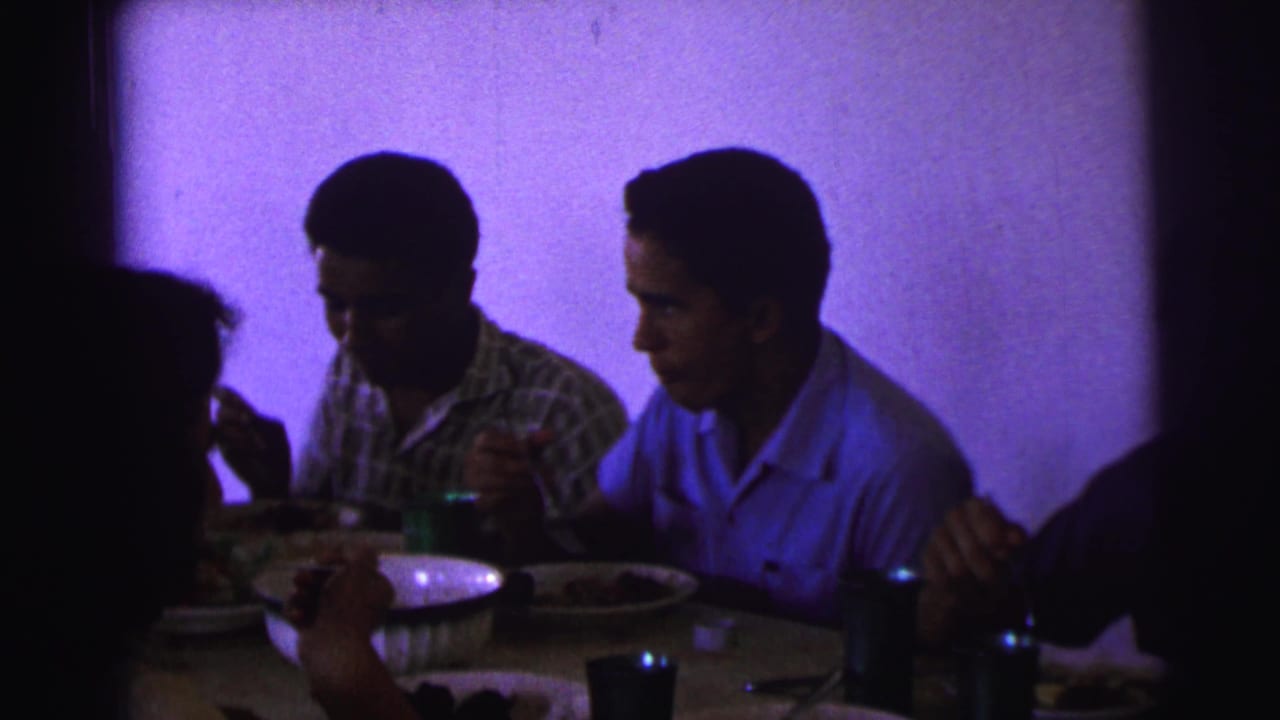 1967 Brazil dining-room frame with two men at the table, food dishes, cups, and low purple 8mm color.