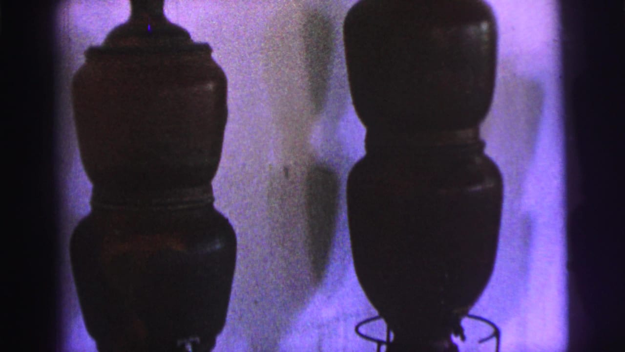 Two tall dark display vessels with rounded sections and a shadowed background.