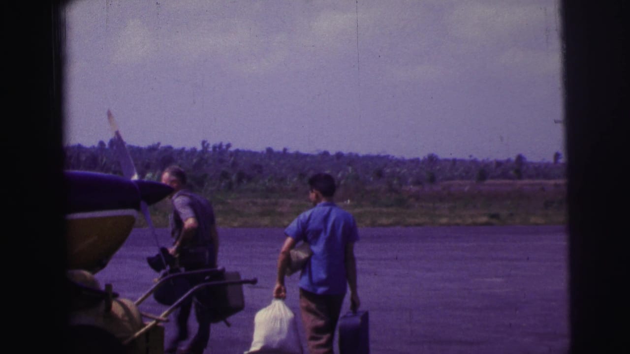 Men with bags and equipment move beside a parked propeller plane on a tarmac.