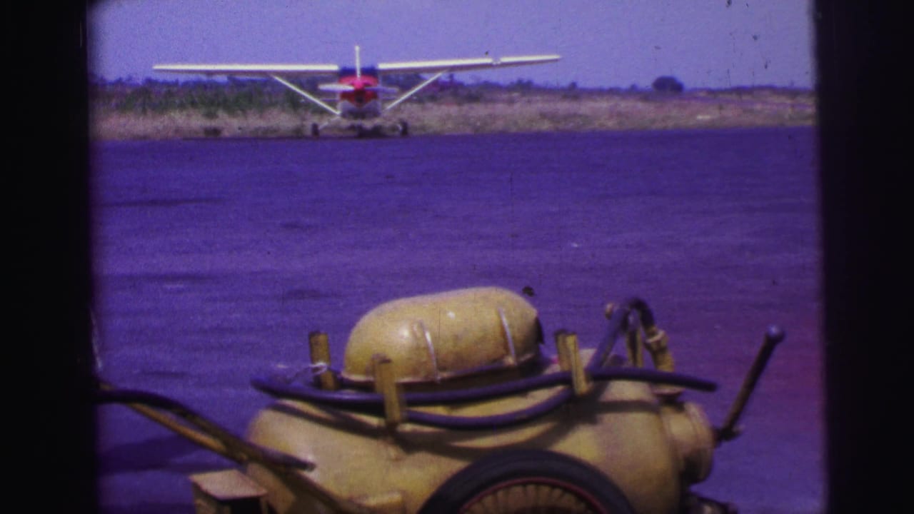 Fuel cart and hoses near the camera with a small seaplane parked in the background.