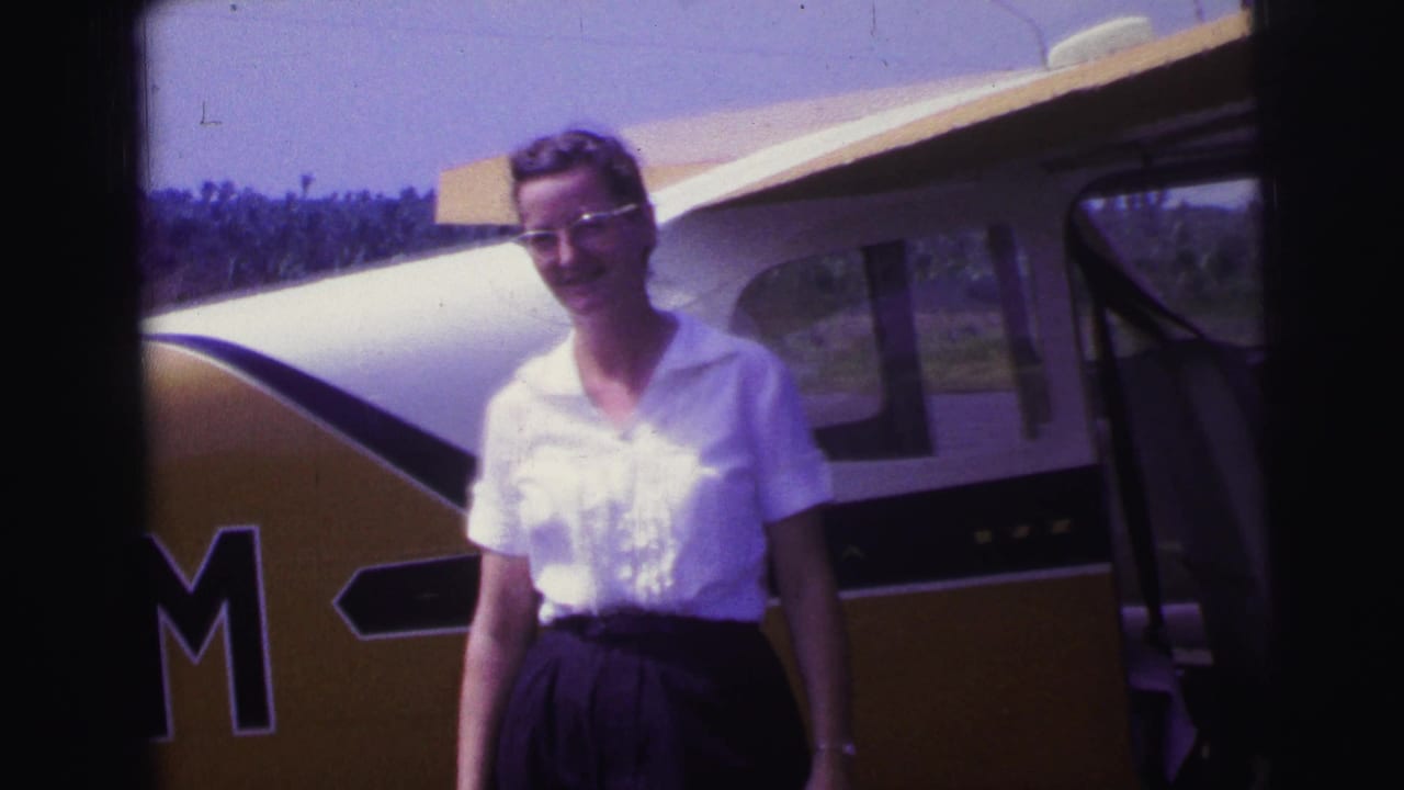 Smiling woman standing in front of the aircraft door and yellow fuselage.