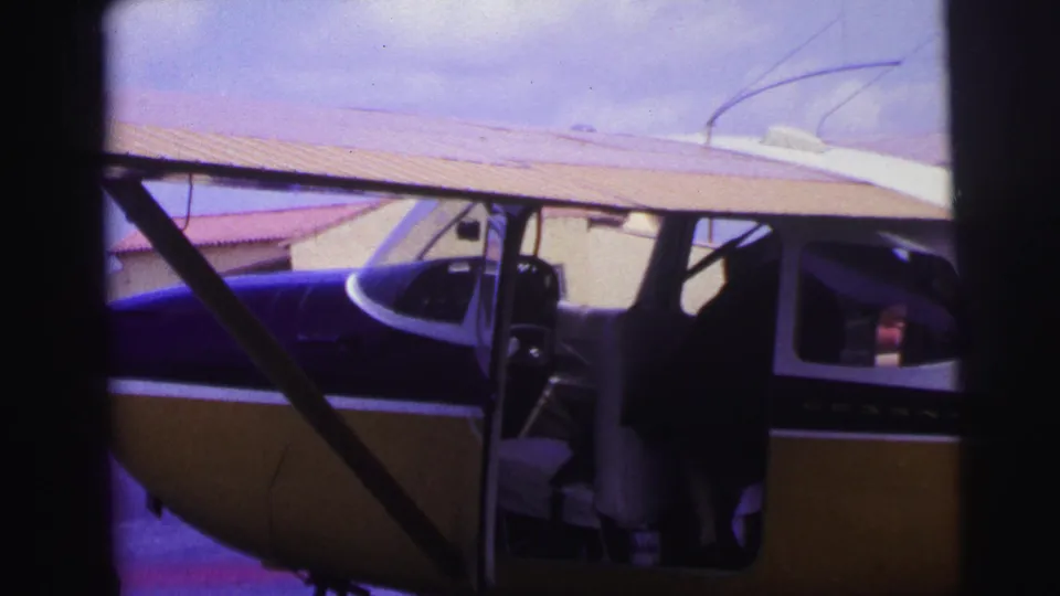 A person leans into the cockpit area of a small single-engine plane at a Brazilian airfield in the 1967 home movie.