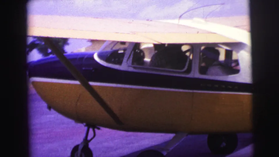Small blue-and-yellow airplane taxiing at a Brazilian airfield in 1967, with cockpit windows and possible occupants visible.
