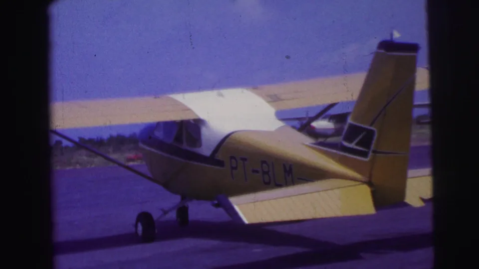 1967 Brazil 8mm frame of the yellow and white PT-BLM aircraft moving forward with another plane in the background.
