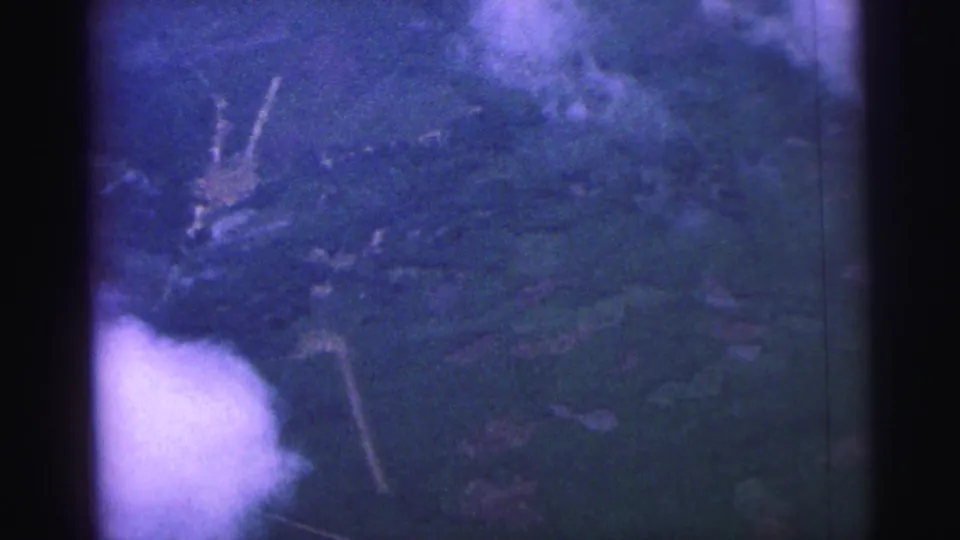 1967 Brazil 8mm frame showing an overhead landscape with hills or fields partly obscured by bright cloud and film-edge shadow.