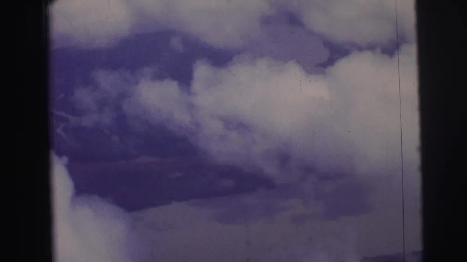1967 Brazil aerial travel frame showing cloud cover above faint terrain, with 8mm gate edge and faded color visible.