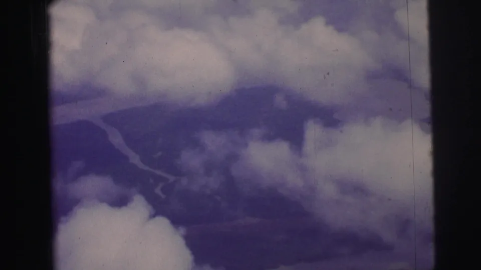 1967 Brazil 8mm aerial frame showing cloud banks above distant land and a faint river bend, with soft focus and film edges.