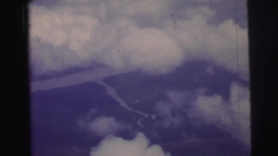 Soft 1967 8mm aerial view over Brazil, with cloud patches crossing distant terrain and a winding river.