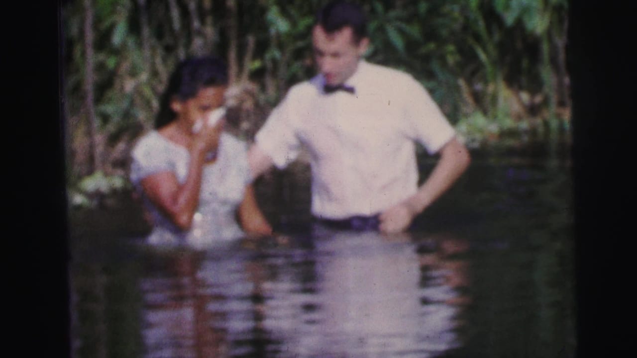 Woman in a light dress stands in shallow water beside a man in a white shirt and bow tie.