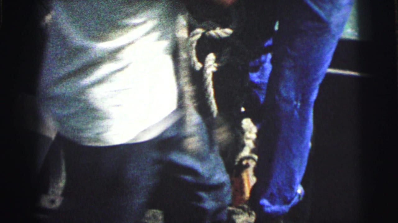 1967 Brazil 8mm frame showing partial sailors in blue trousers and a light shirt near thick rope on a boat deck.