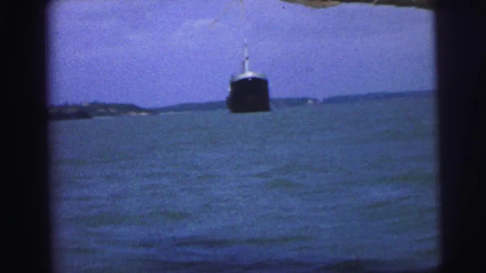 Wide 1967 Brazil 8mm view of a large vessel on a bay, with water, distant land, and dark film-frame edges.