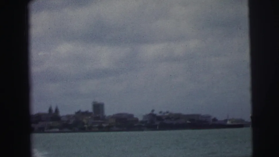 Distant Brazilian waterfront skyline across the harbor, framed by dark 8mm gate edges.