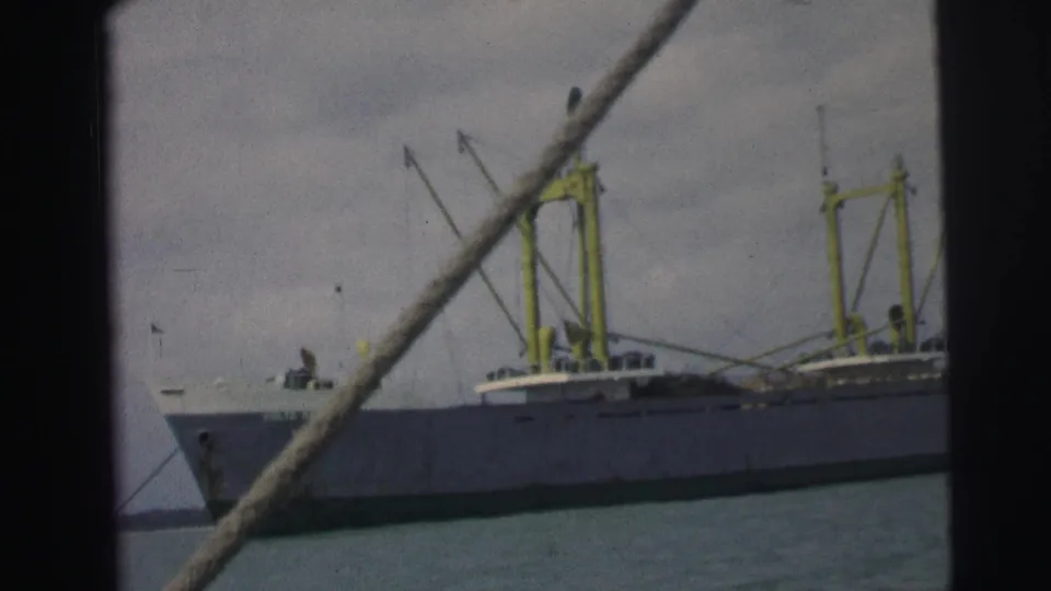 1967 Brazil 8mm frame showing the bow and long side of a cargo vessel, with cranes and foreground rope visible.