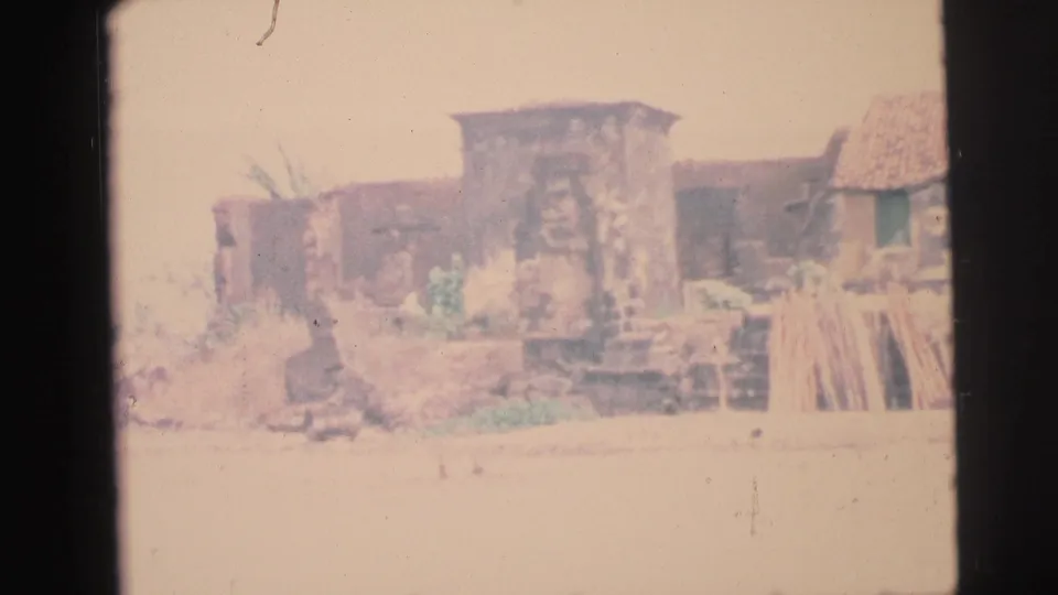 1967 Brazil 8mm frame showing a weathered shoreline structure with rough stone, pale ground, and stacked boards.