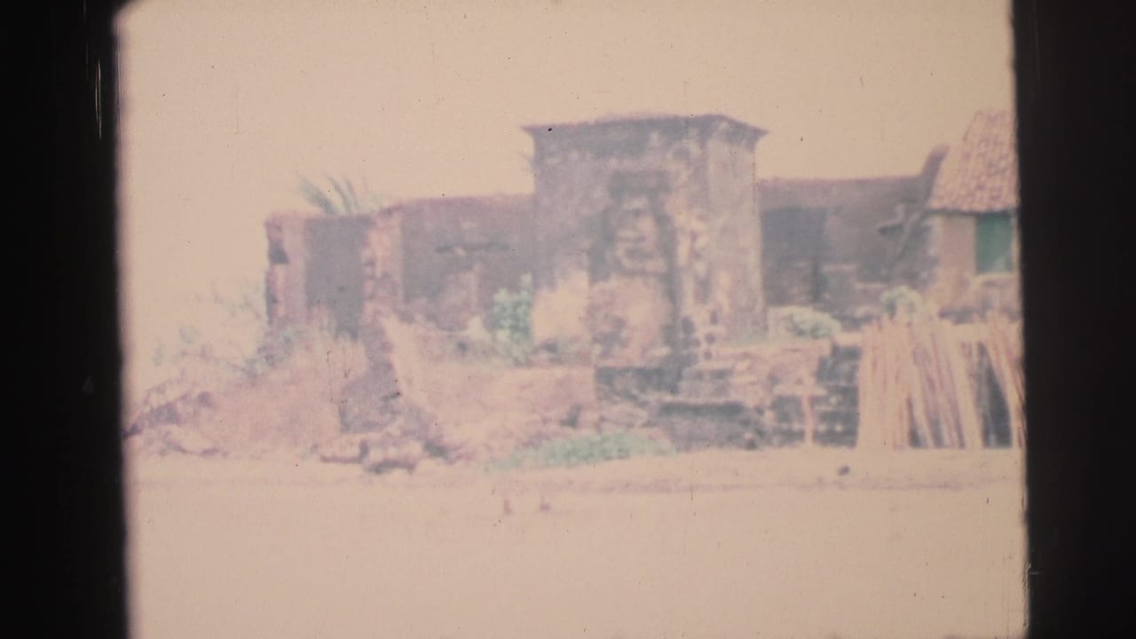 Weathered coastal structure with rough stonework and boards near the shore.