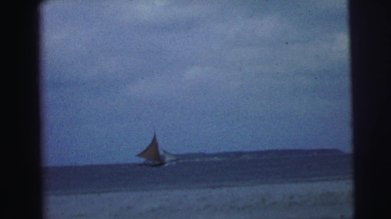Distant sailboat near a low horizon on blue water with cloudy sky above.