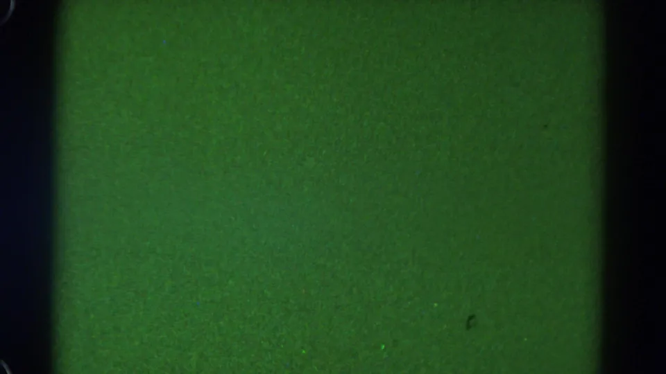 1967 Colorado 8mm frame with solid green color, black side edging, analog grain, and isolated speckles.