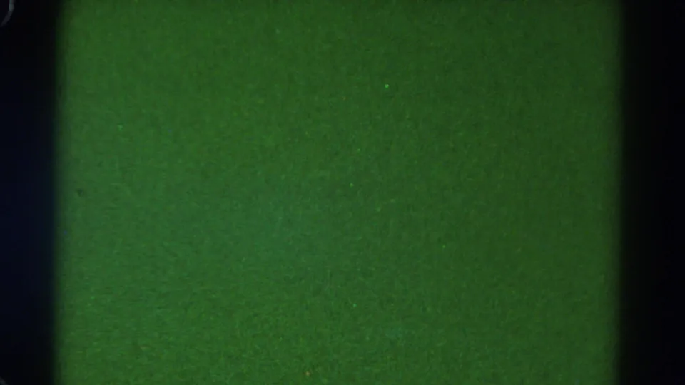 Grainy green 8mm frame with vertical black bands, likely the train-window structure before the exterior view brightens.