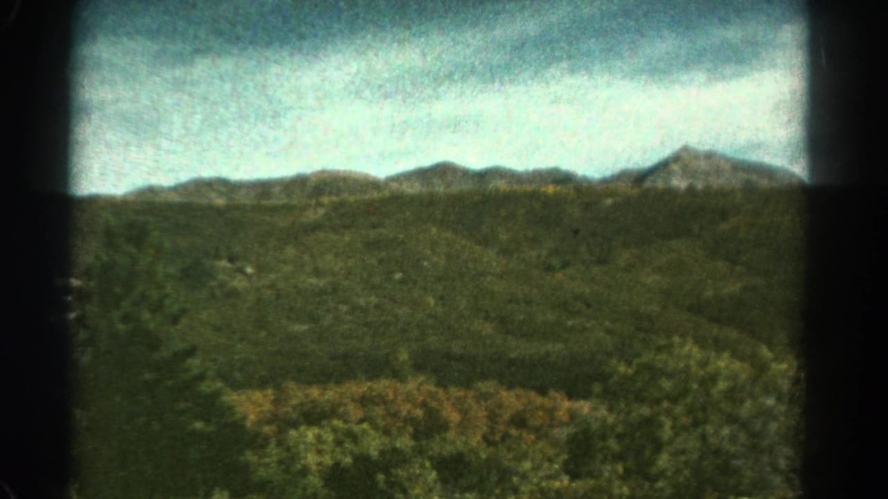1967 Colorado 8mm frame showing a green mountain valley and distant ridges viewed from a moving train.