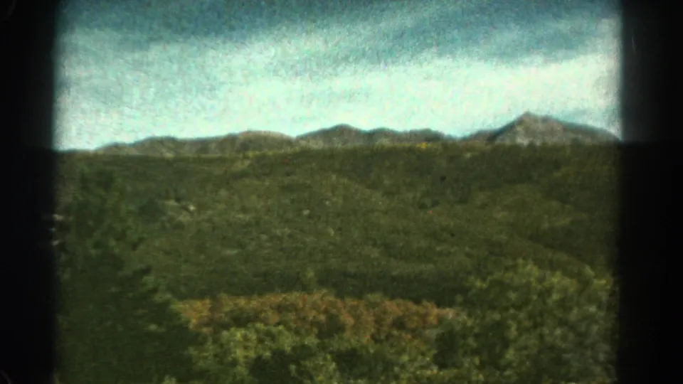 1967 Colorado 8mm frame showing a green mountain valley and distant ridges viewed from a moving train.