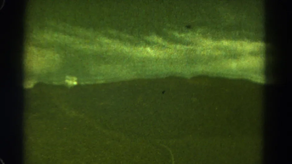 1967 Colorado roadside landscape with a pale curving road, grassy hillside, distant mountain ridge, and green aged-film color cast.