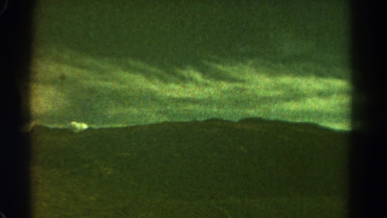 1967 8mm Colorado view of a dark mountain horizon under a cloudy green-tinted sky, divided by visible film or contact-sheet borders.