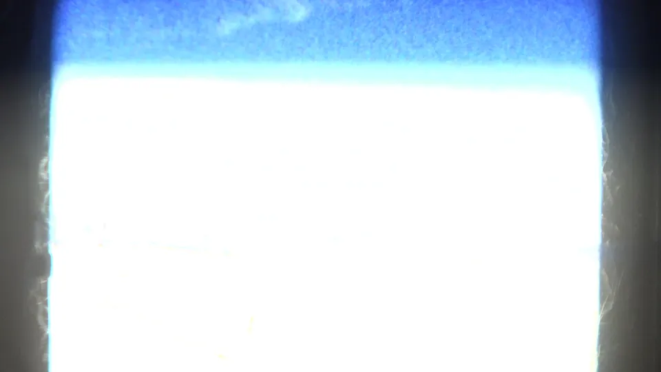 Abrupt overexposed 8mm transition frame, with bright white center, blue-tinted edge, and visible film texture from the scan.