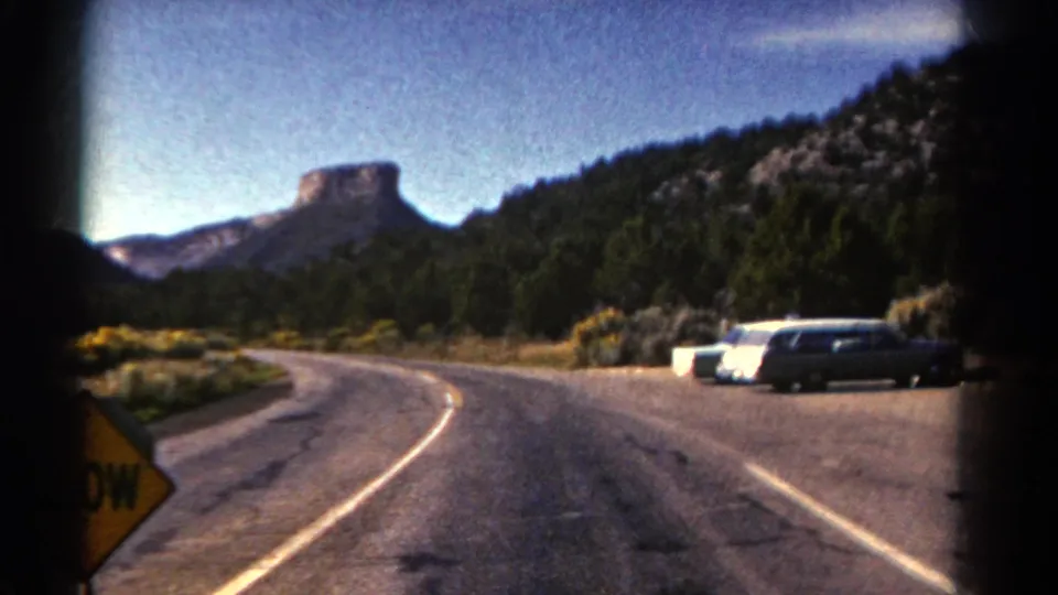 The 1967 Colorado footage shows a road curving through a roadside stop with parked cars, forested hills, and a partial yellow sign.