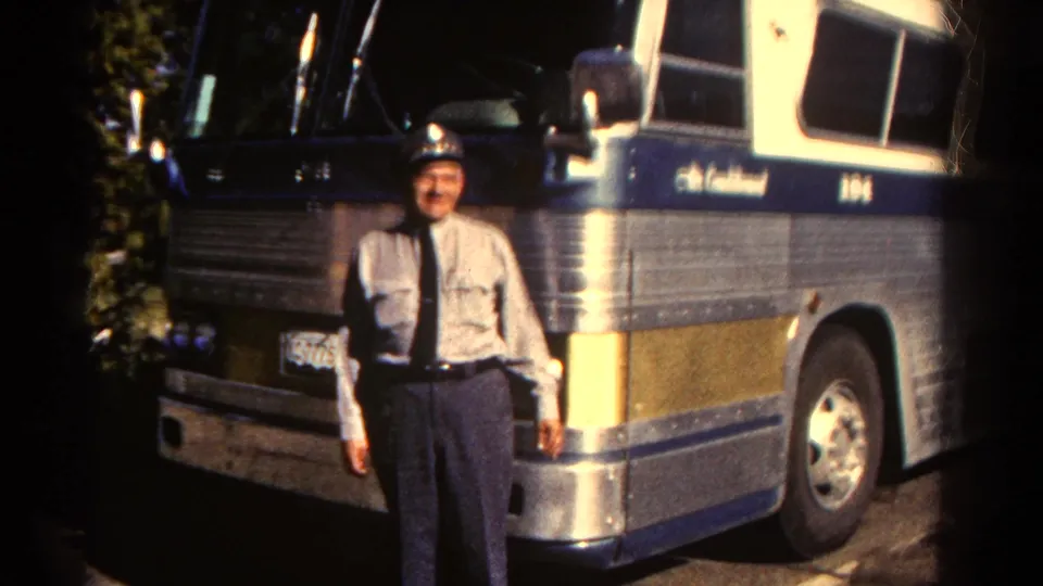 A uniformed adult bus driver stands outside an Air Continental motorcoach with blue and gold striping in 1967 Colorado footage.