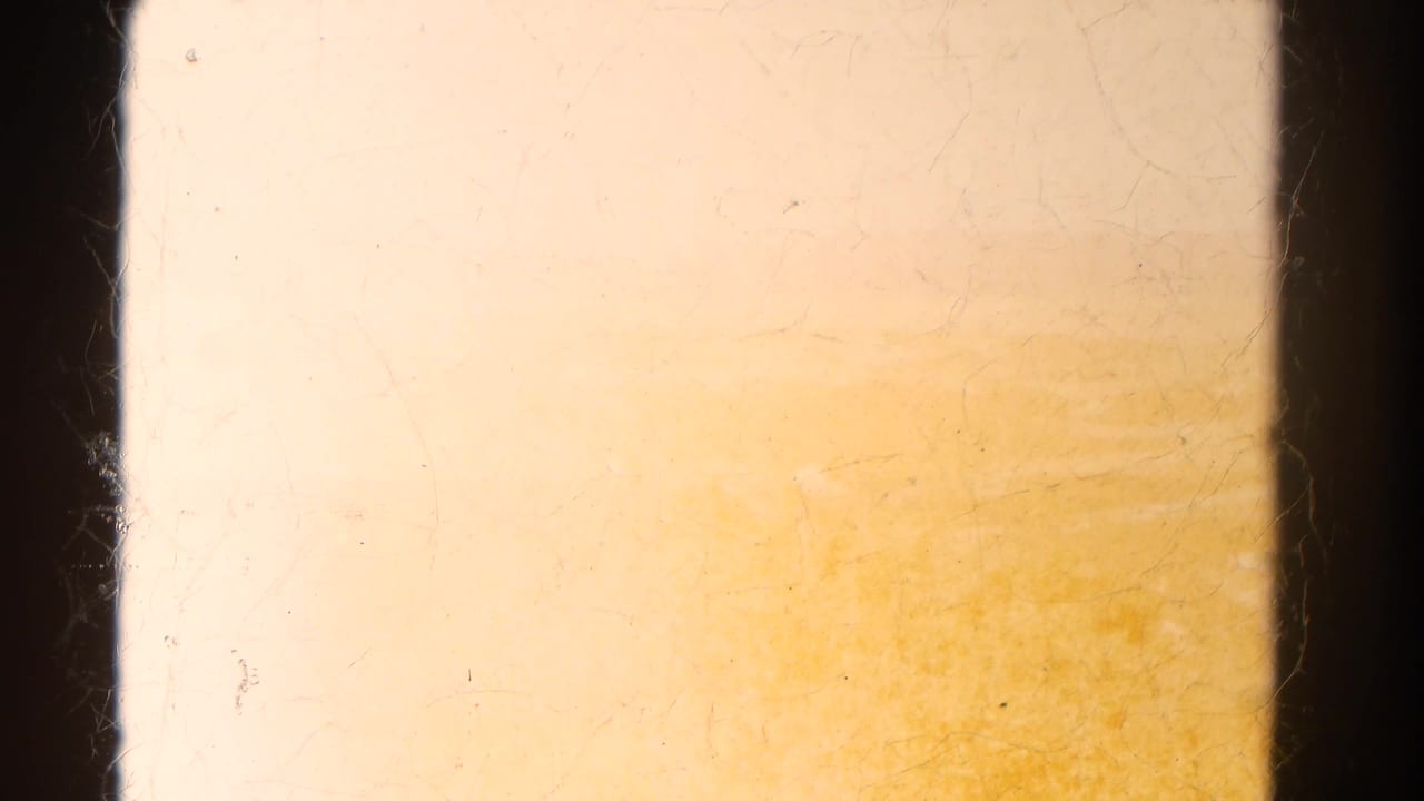 Overexposed film frame with dark gate edges and warm yellow staining.