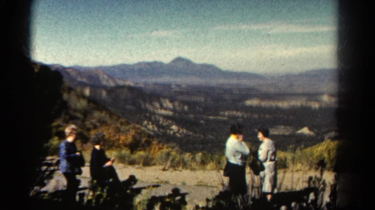 A Colorado scenic overlook in 1967, with two women standing on the right, another seated at left, and a broad valley stretching to distant mountains.