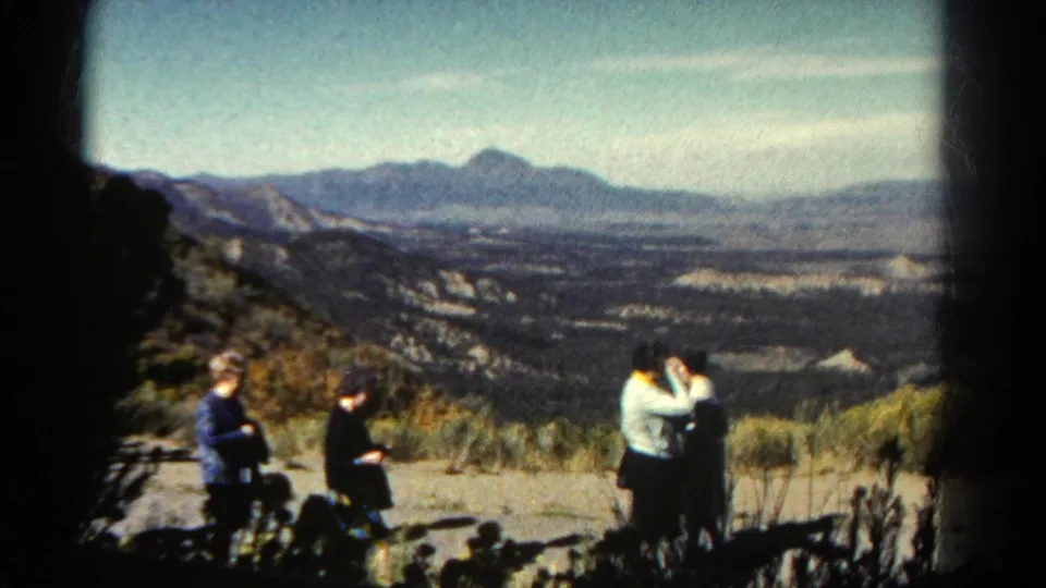 In a soft 8mm frame from Colorado, two women stand close together at right while a seated wheelchair user and another woman remain near the overlook at left.