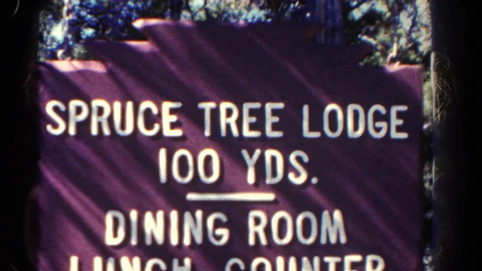 Close-up of the Spruce Tree Lodge directional sign in documented 1967 Colorado footage, including dining room and lunch counter text.
