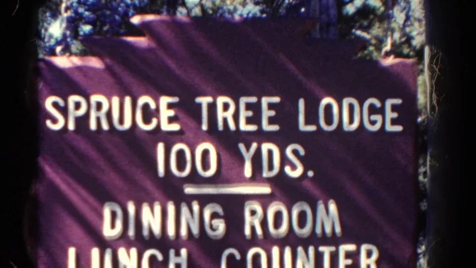 Final 1967 Colorado 8mm close view of the purple Spruce Tree Lodge sign, with white lettering and partial lunch counter line.