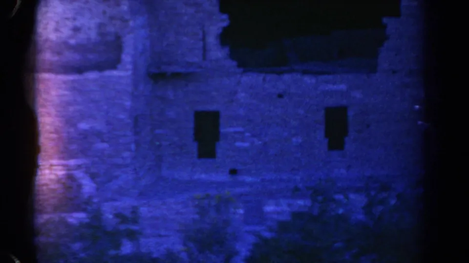1967 Colorado 8mm frame showing a blue-shifted ruin wall with two small rectangular openings and a dark upper recess.
