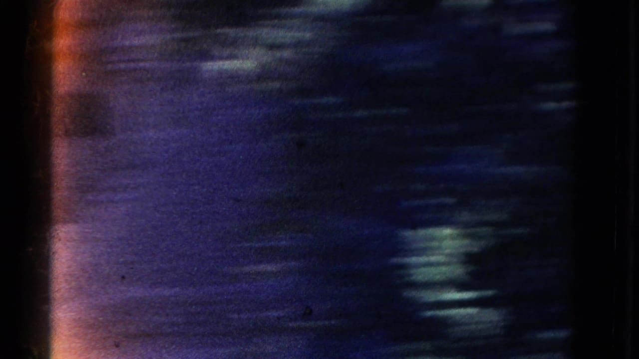 Dark, blurred 8mm frame with streaked canyon tones and film-edge flare.
