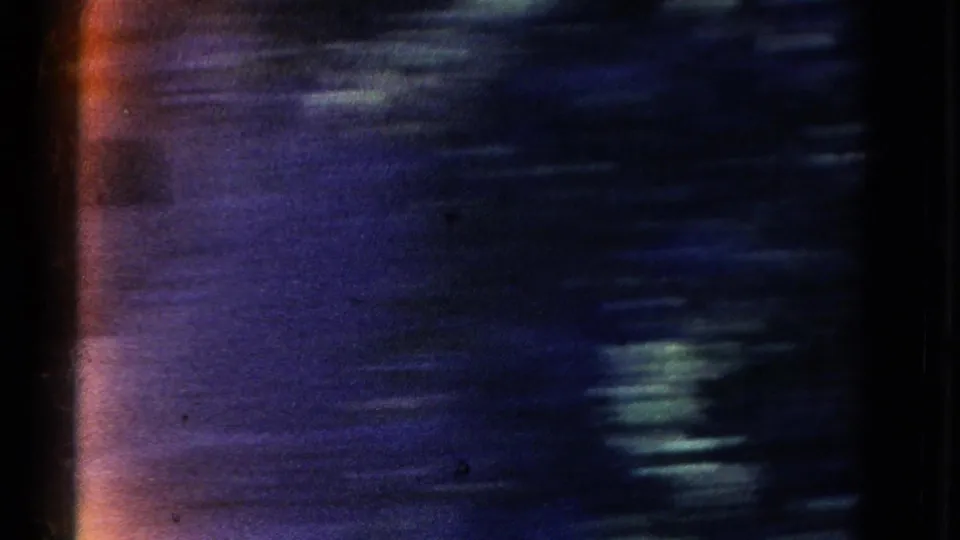 Opening 1967 8mm frame appears dark and motion-blurred, with blue-purple canyon texture and orange edge flare from the film scan.