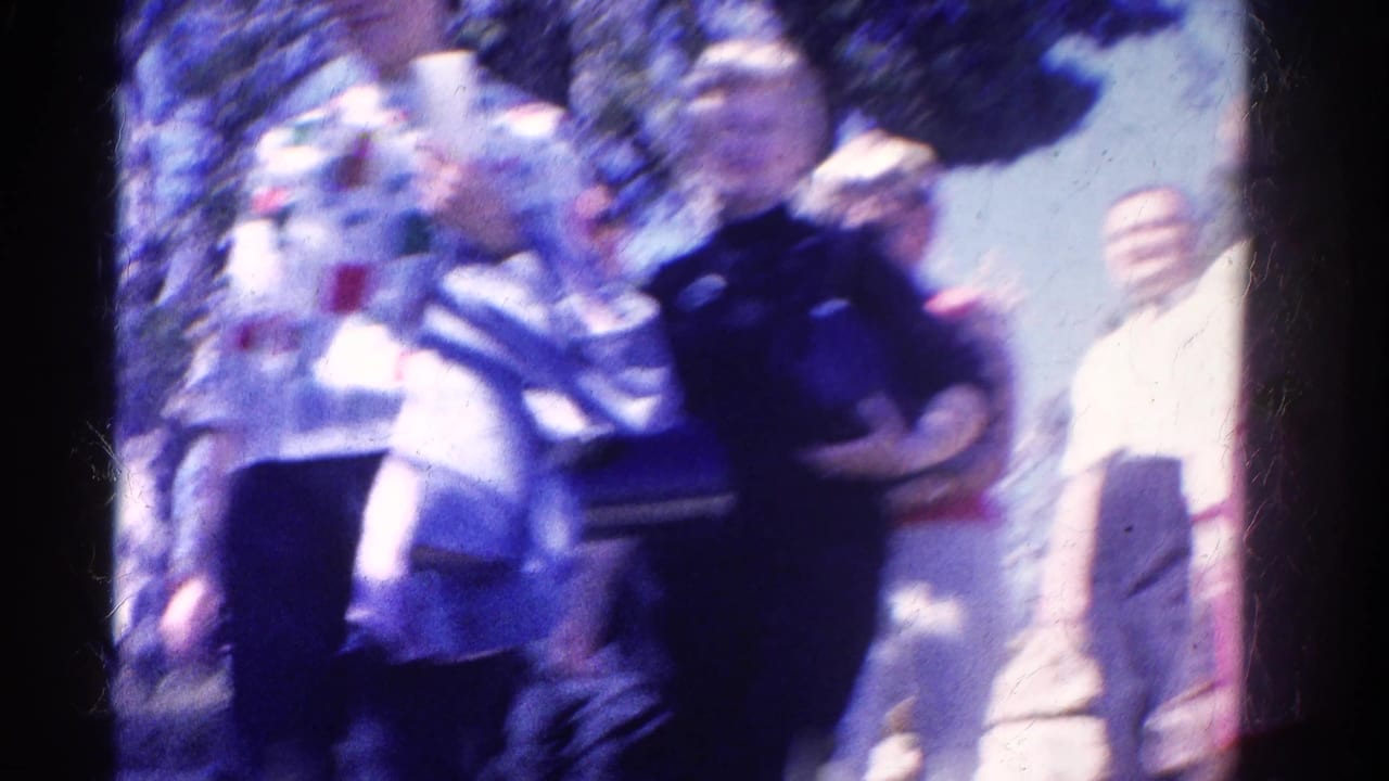 Soft 1967 Colorado 8mm frame of women passing close to the camera on a sunny outdoor path, with figures blurred by motion.