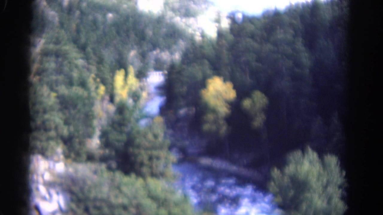 Winding river below a forested valley with yellow autumn trees and rocky slopes.