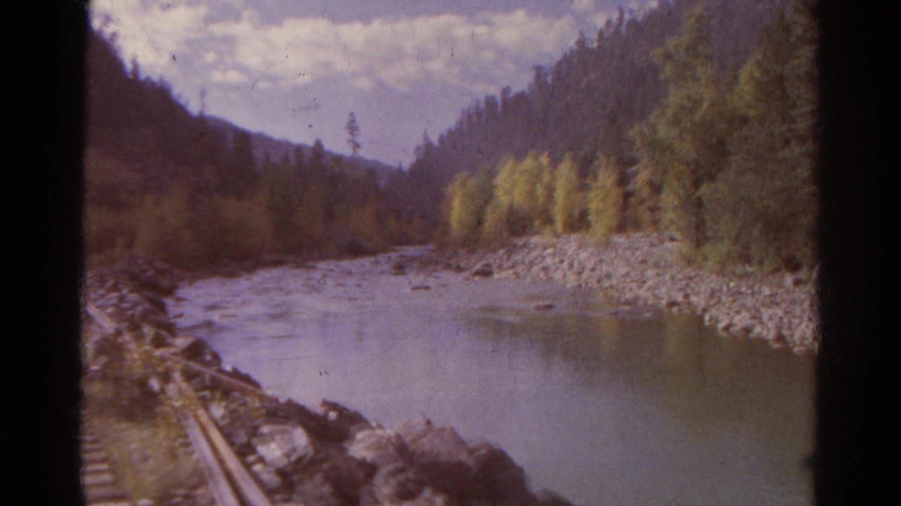 Colorado mountain river and forested banks pass by in a 1967 8mm train-view home movie frame.