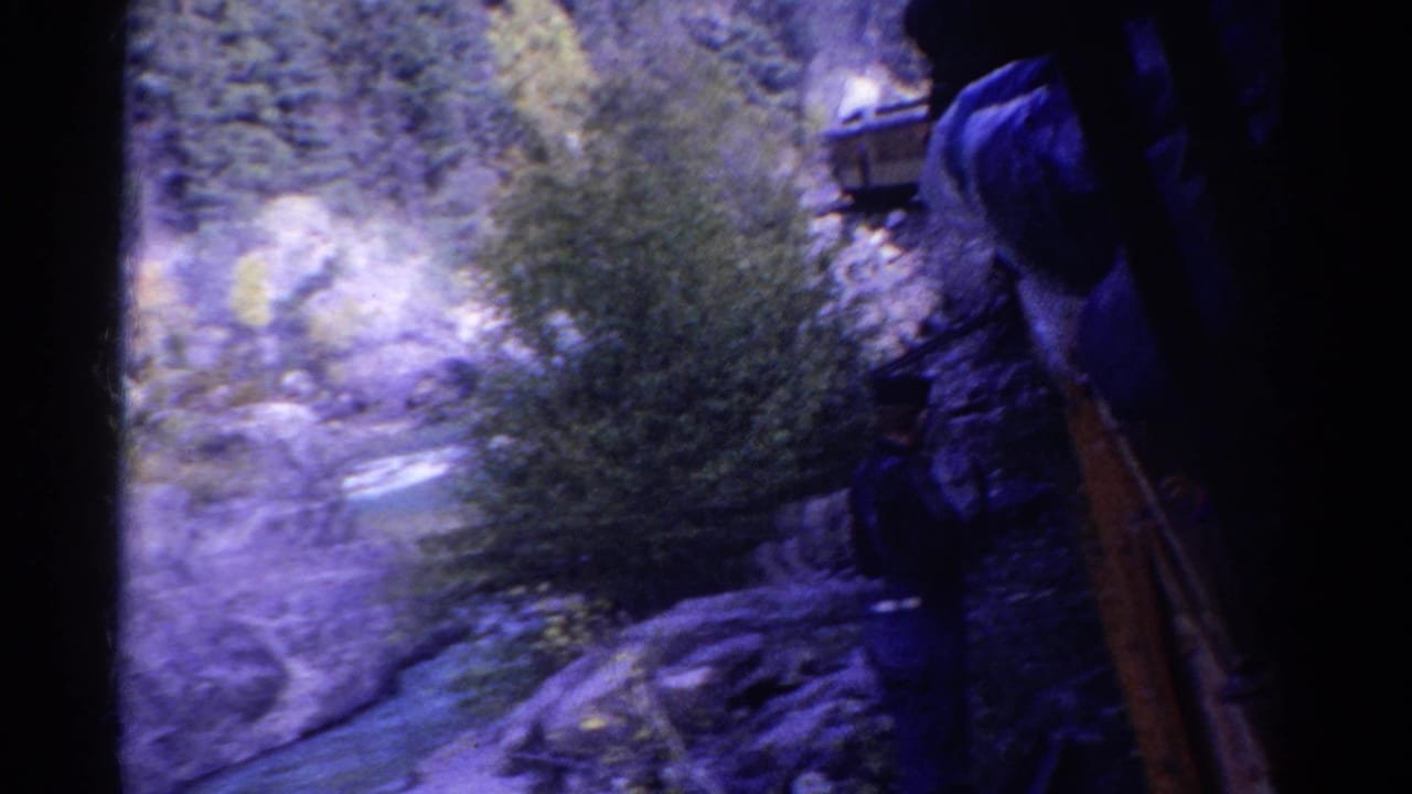 1967 Colorado home-movie frame of a rocky river gorge, with a dark-clothed person partly visible near the right edge.