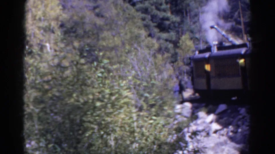 1967 Colorado 8mm view of steam rail machinery moving or sitting close to the camera in a rocky forest pass.