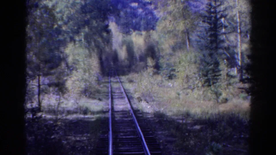 1967 Colorado 8mm still showing a passenger-like view down rails through wooded terrain and soft shaded vegetation.