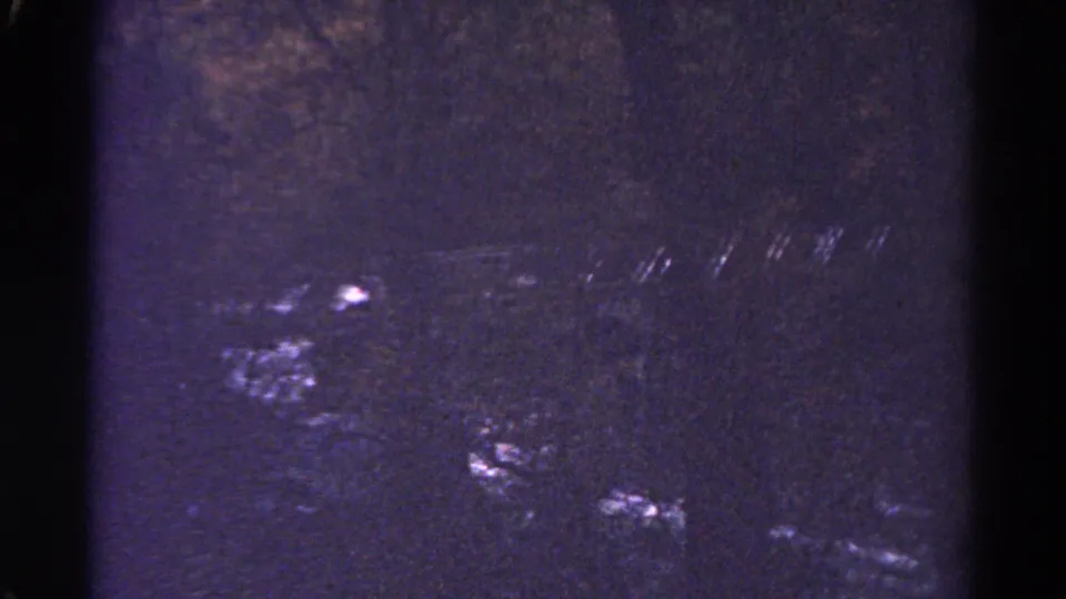 Colorado 1967 8mm frame with mostly dark exposure, purple tint, faint water highlights, and visible film surface marks.