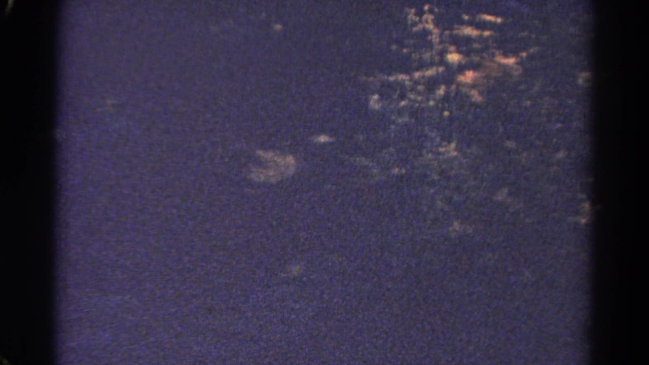 Dark, grainy view of forested hills through an 8mm film frame.