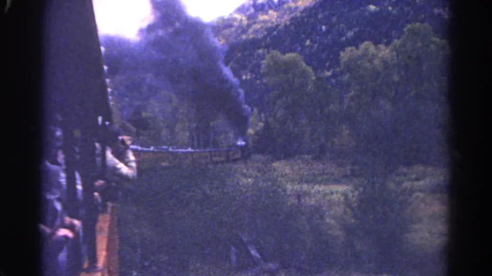 1967 Colorado 8mm frame showing the side of a steam train and smoke rising across dense forest.