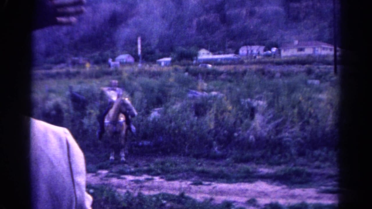 1967 Colorado 8mm frame with a horseback rider in a hat moving through brush as the vehicle window and passenger remain in view.