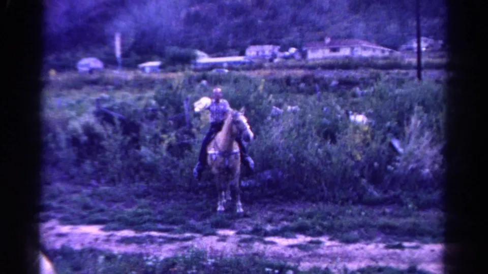 1967 Colorado 8mm frame showing a rider on horseback in an overgrown rural area with small houses in the distance.